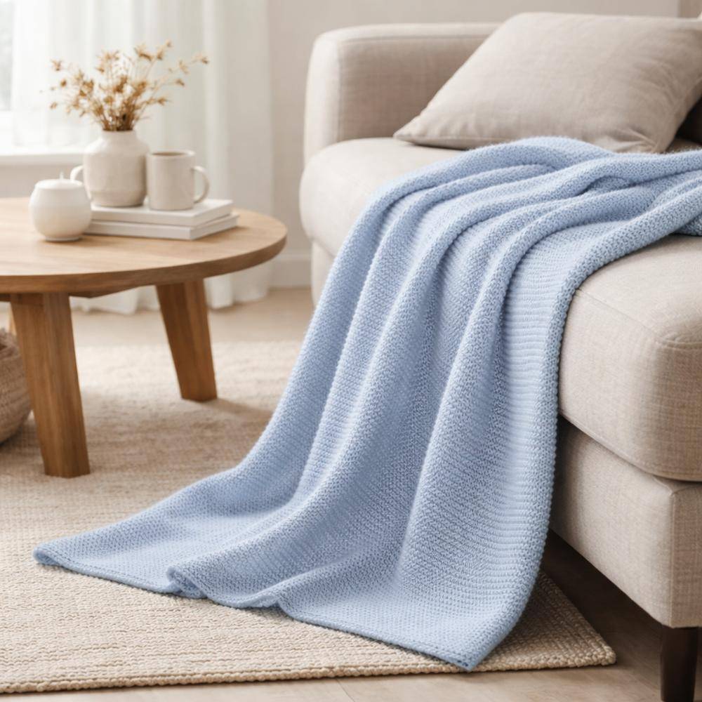 Marc O'Polo Plaid Nordic Knit Calm Blue auf Sofa im hellen Wohnzimmer drapiert, gemütliche Wohnatmosphäre